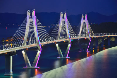 Illuminated suspension bridge over river at night