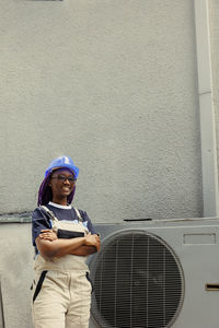 Portrait of young woman standing against wall