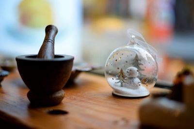 Close-up of mortar and pestle with snow globe on table