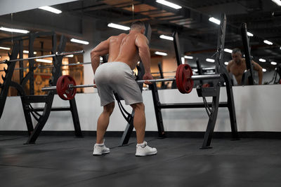 Rear view of shirtless man sitting in corridor