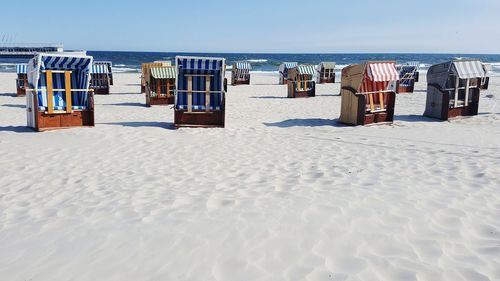 Hooded chairs on beach against sky