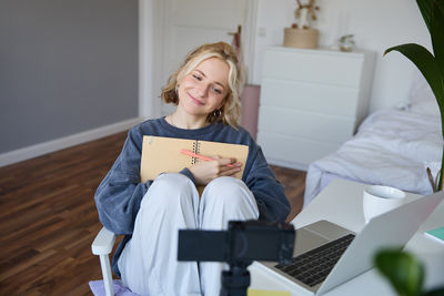 Portrait of young woman using mobile phone while sitting on sofa at home