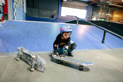 Little boy crouches down to set up his skateboard