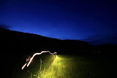 Person on illuminated field against sky at night