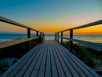 Pier over sea against sky during sunset