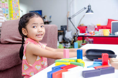 Portrait of smiling girl playing with toys at home