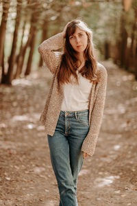 Portrait of a girl with brown hair, in a cardigan, on a walk in the forest.