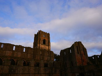 Low angle view of old ruin building against cloudy sky