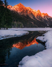 Snowcapped alps reflected in anterselva lake  at sunset in winter. snow and ice in the foreground.