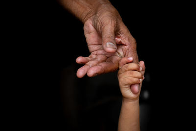 Midsection of person holding hands against black background