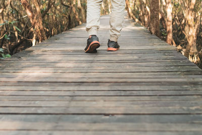 Low section of man walking on boardwalk