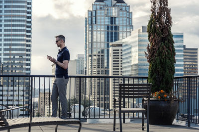 Side view of businessman using smart phone while standing on building terrace
