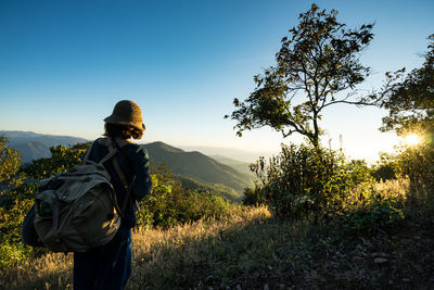 Rear view of woman hiking on mountain against clear blue sky