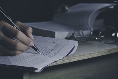 Midsection of woman writing in book