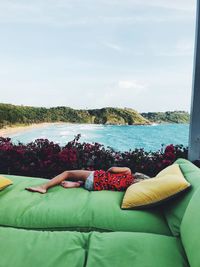 Girl lying on bed against sea