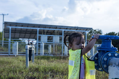 Girl opening a water valve with solar panels in the background. person