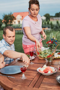 Family having a meal from grill during summer picnic outdoor dinner in a home garden