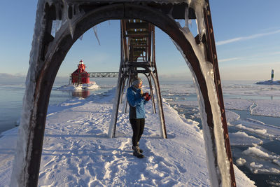 Teen age girl taking pictures at a lighthouse in the winter