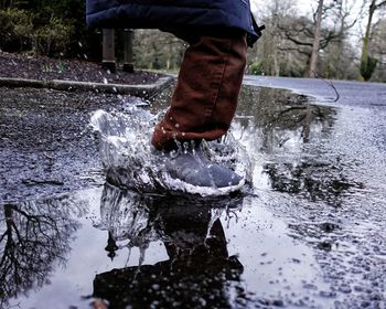 Low section of man splashing water in puddle