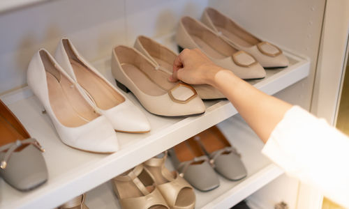 The woman holding shoes in her hands to choose and shopping looking at the shelves of footwear.