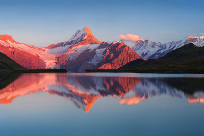 Scenic view of lake by mountains against sky during sunset