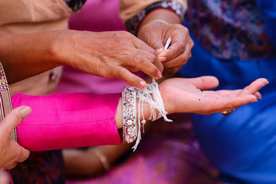 Midsection of woman holding hands,baisi wrist-binding ceremony , the ancient of thail people.