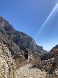 Rear view of man on rock against sky