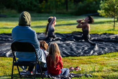 Rear view of people sitting on grassland