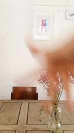 Flower vase on table against wall at home