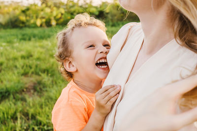 Close-up of cheerful boy embracing mother in park