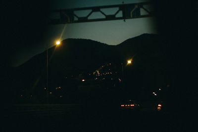 Illuminated street lights against sky at night