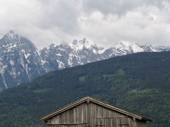 House amidst trees and mountains against sky