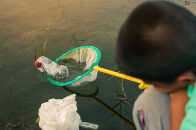 Rear view of boy holding fishing net in river