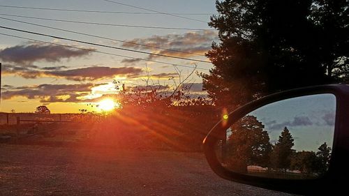 Close-up of wet car on road against sunset sky