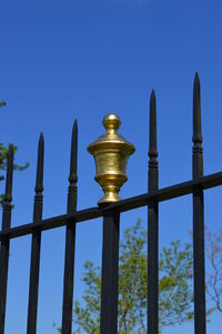 Low angle view of metal fence against clear blue sky