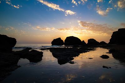 Rocks on sea against sky during sunset