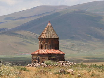 Built structure on field by mountain against sky