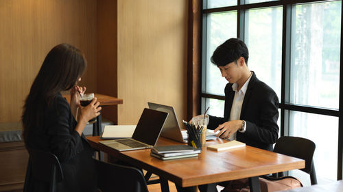 Young man using mobile phone at table