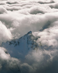 Aerial view of snowcapped mountain against cloudy sky