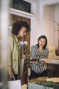 Saleswoman gesturing while sharing digital tablet in fashion boutique