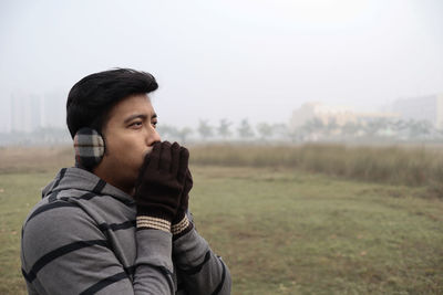 Young man looking away while standing on land