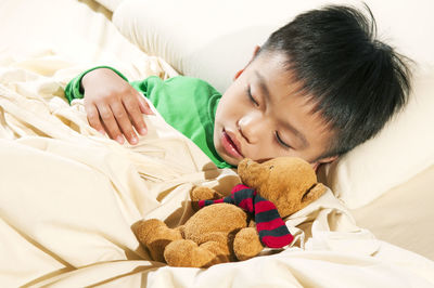 Close-up of boy sleeping with stuffed toy on bed