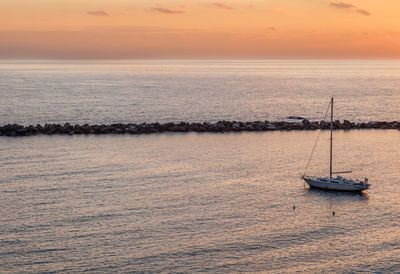 Sailboat on sea against sky during sunset