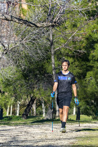 Nordic walking. young person practicing the sport nordic walking with poles in an outdoor park 