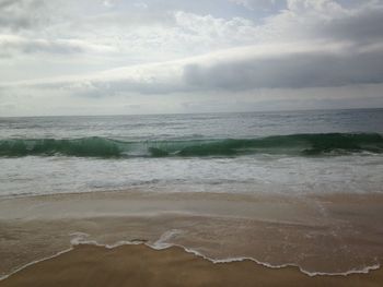 Scenic view of beach against cloudy sky