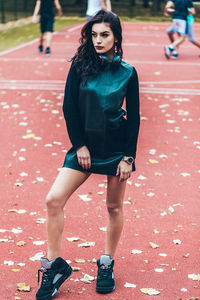 Full length of fashionable woman looking away while standing on basketball court