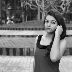 Young woman with hand in hair standing at park