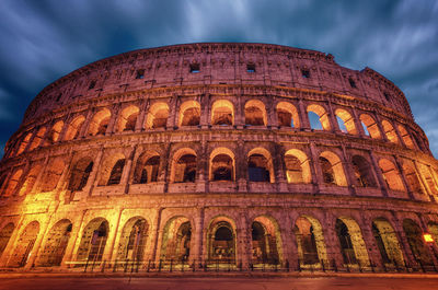 Low angle view of coliseum against sky at dusk