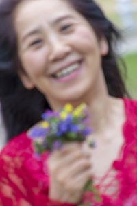 Portrait of smiling woman holding flower head