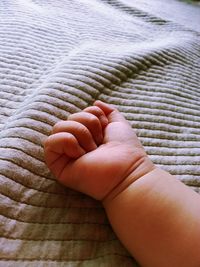 Cropped child hand on bed at home